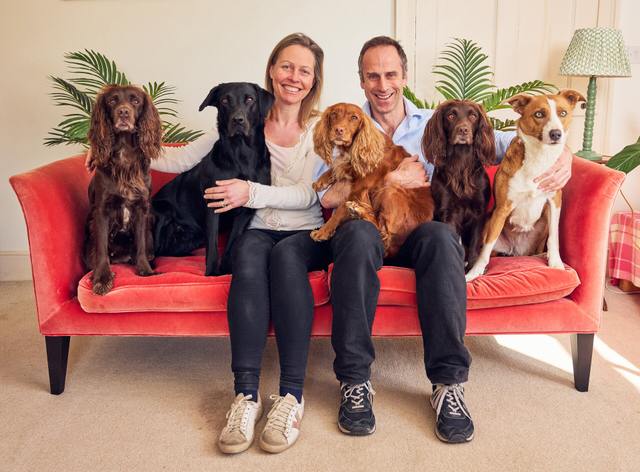 Charlie and Alex on a sofa with five dogs